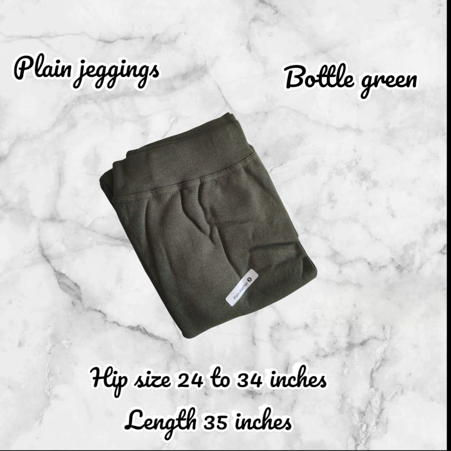 Folded plain jeggings in bottle green on a marble background with text about size and length.