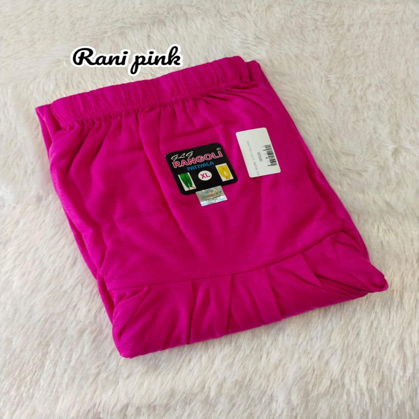 Folded rani pink fabric with a label on a light beige background