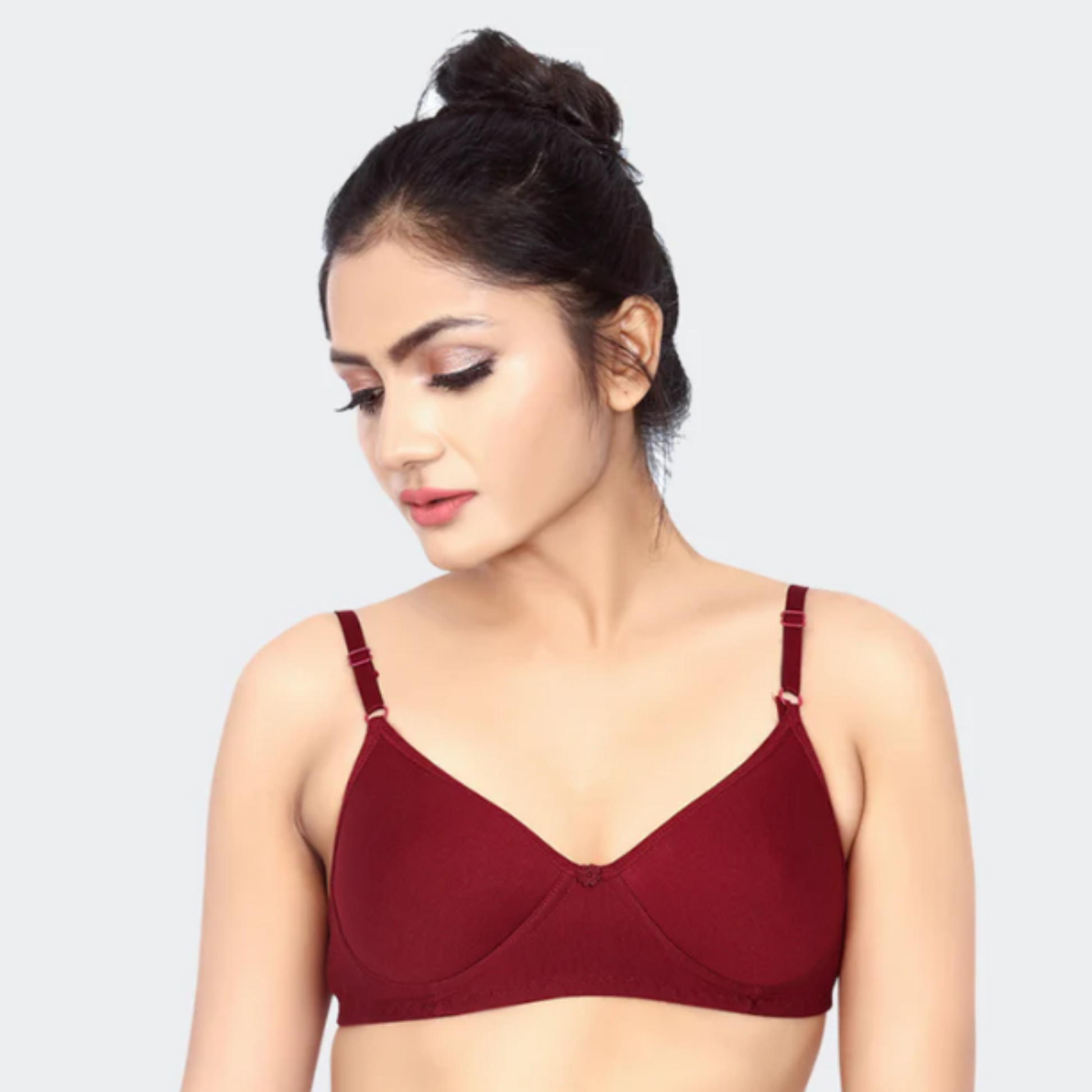 Woman wearing a maroon bralette against a light gray background