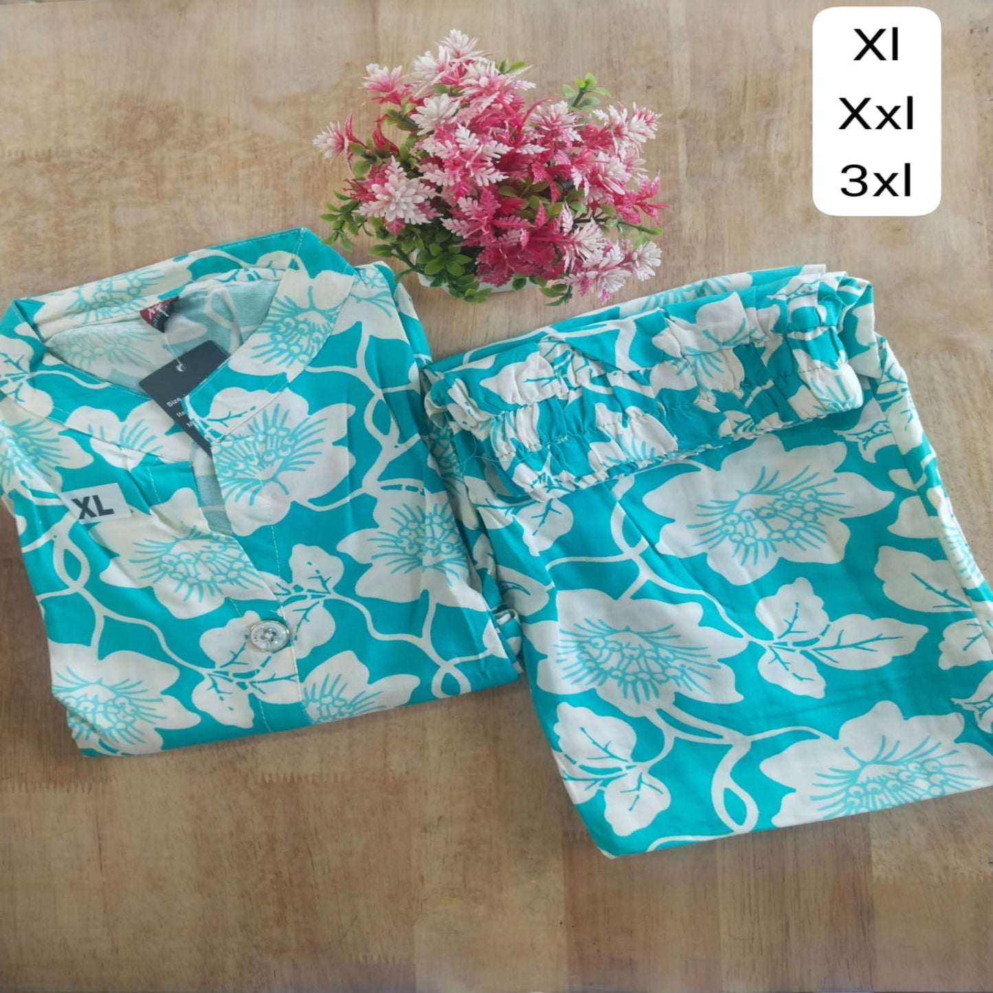 Turquoise floral pants with size labels on a wooden surface