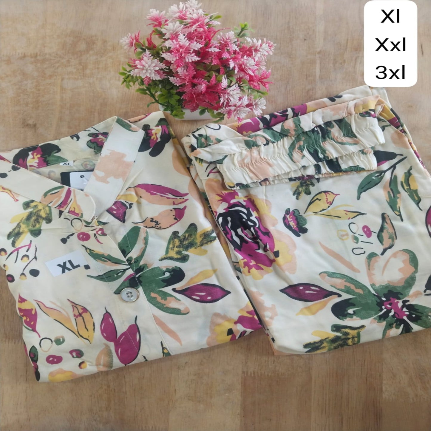 Floral-patterned pants displayed on a wooden surface with a small bouquet of flowers.