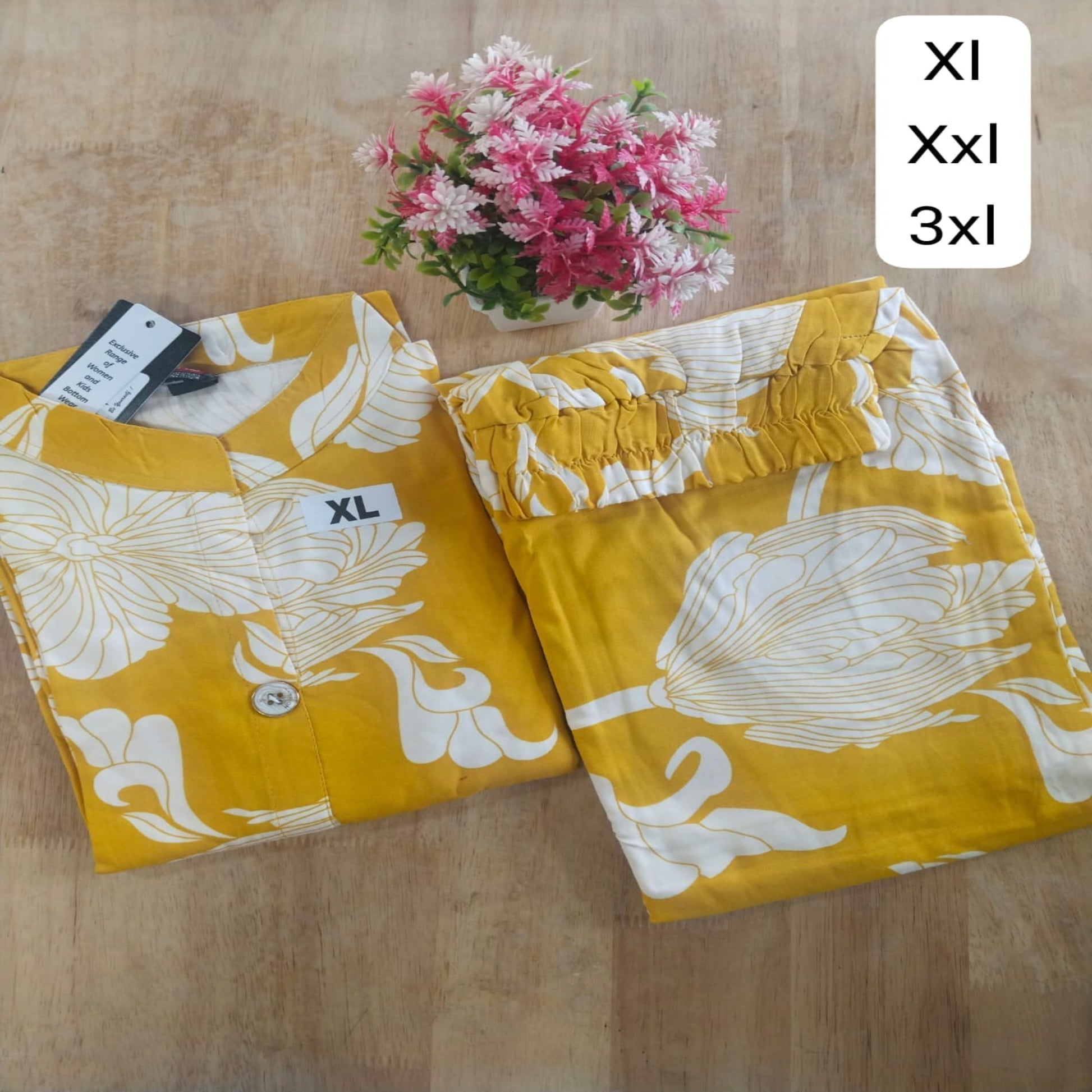 Yellow pants with floral pattern on a wooden surface, with size labels XL, XXL, and 3XL.