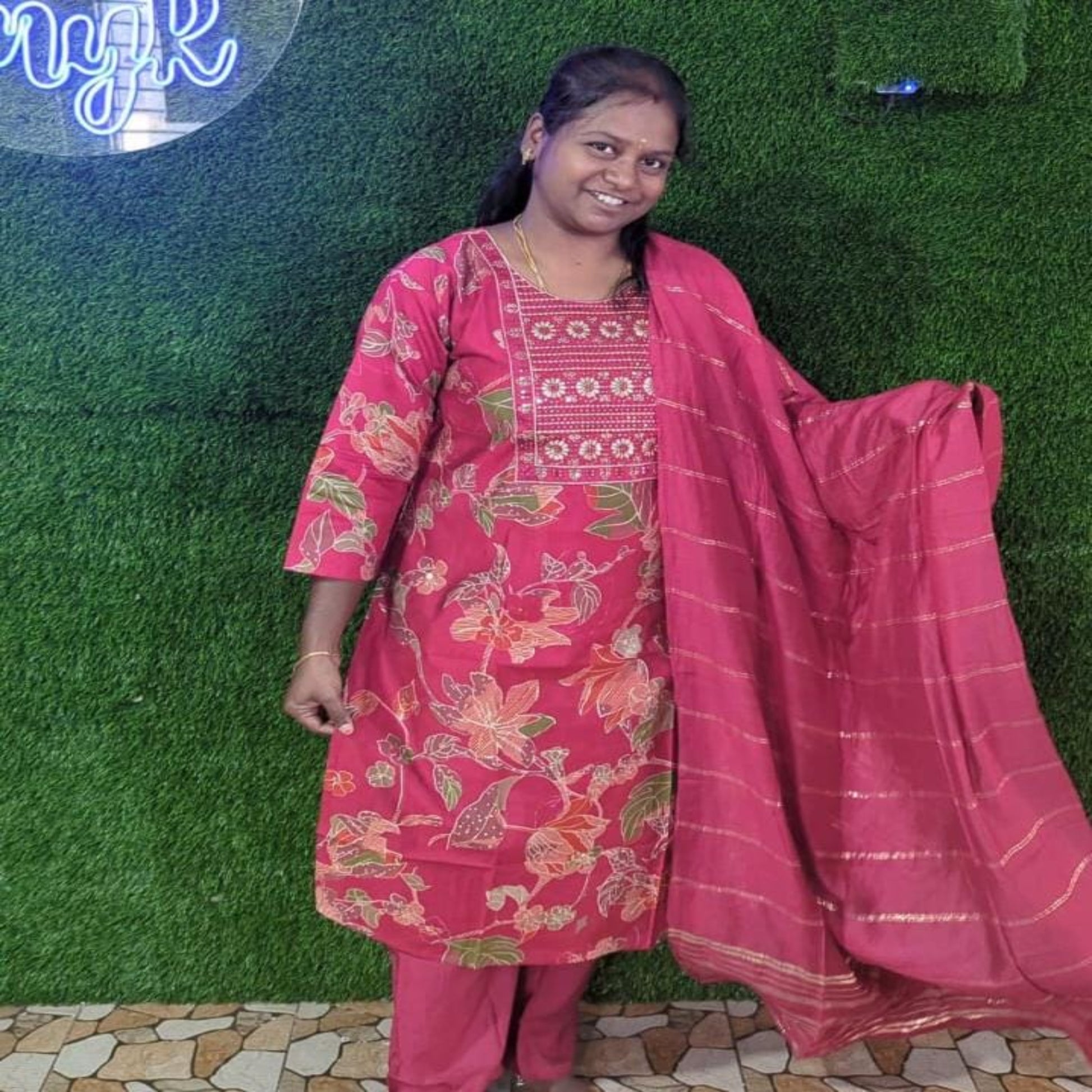 Woman in a pink traditional outfit with a matching dupatta against a green grass background