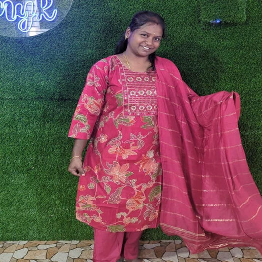 Woman in a pink traditional outfit with a matching dupatta against a green grass background