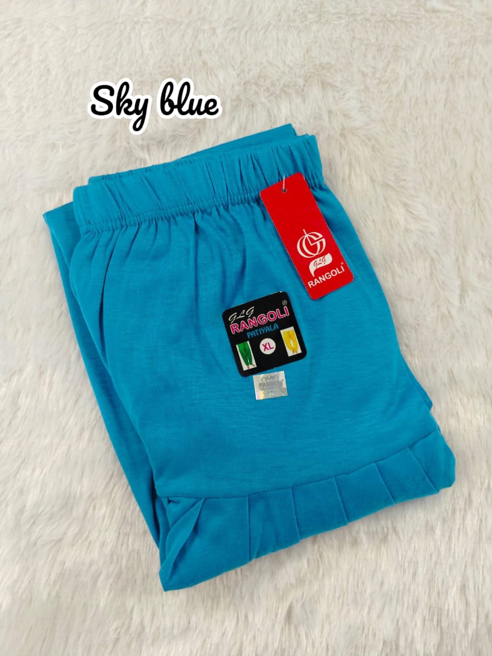 Folded blue pants with a red tag on a light gray background